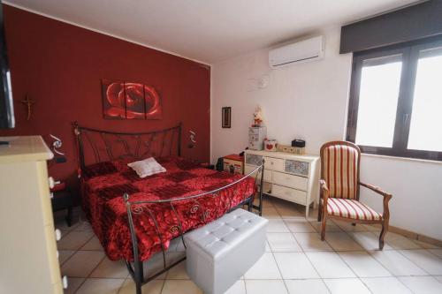een slaapkamer met een rood bed en een stoel bij Villa delle Palme in Lendinuso