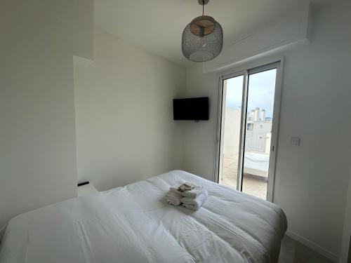 une chambre blanche avec un lit et une fenêtre dans l'établissement Superbe T2 en dernier étage, à Antibes