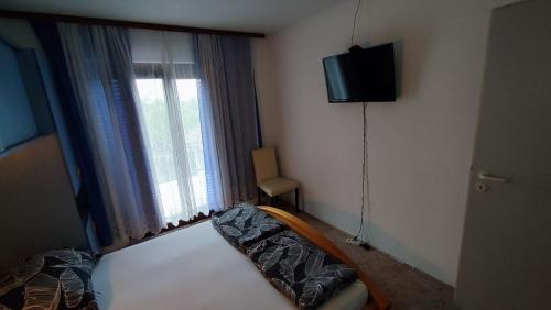 a bedroom with a bed and a television and a window at House Bosko Best place for everyone 
