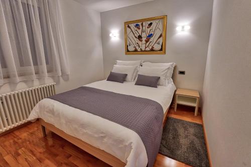 a bedroom with a large white bed with two pillows at Apartments Bagar in Portorož