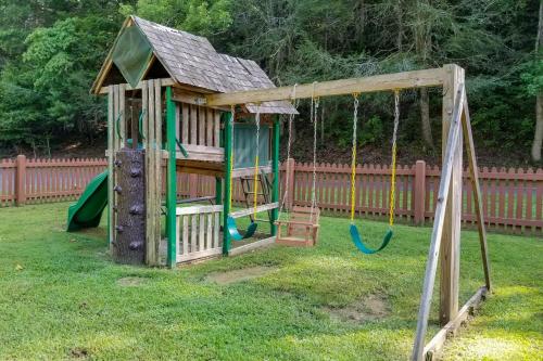 a wooden playground with a swing in a yard at Mama Bear's Dream in Sevierville