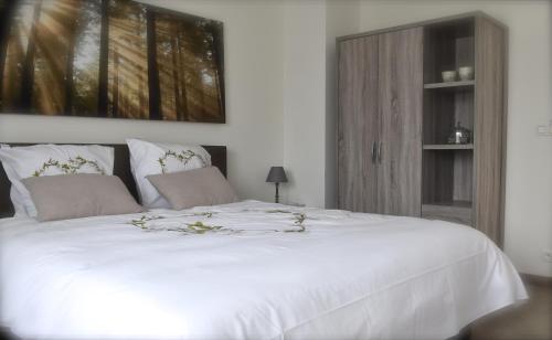 a white bed with two pillows on top of it at de minnetuin in Wachtebeke