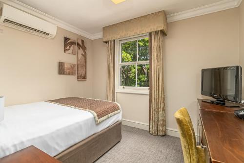 a bedroom with a bed and a tv and a window at Mercure Salisbury White Hart Hotel in Salisbury