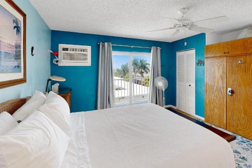1 dormitorio con cama blanca y balcón en Skipjack Resort & Marina #404, en Marathon