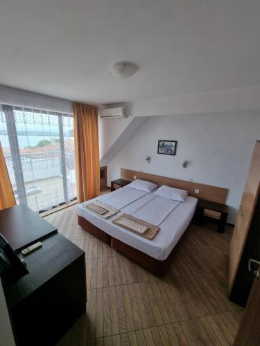a bedroom with a bed and a large window at Стаи за гости Мистрал in Primorsko