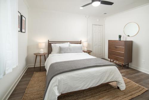 a white bedroom with a large bed and a mirror at The Victorian Inn Blowing Rock in Blowing Rock