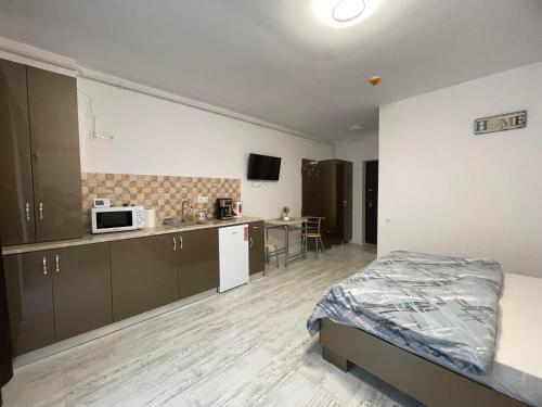 a bedroom with a bed and a kitchen with a microwave at Garsoniera la Mare in Saturn