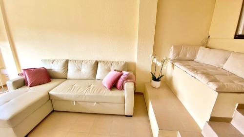 sala de estar con sofá blanco y almohadas rosas en Sonora Golf and rest apartment, en Santa Cristina d'Aro