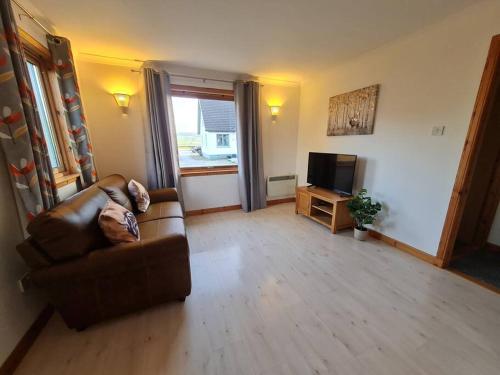 a living room with a couch and a television at Kings Reach - Crinan Cottage in Lochgilphead