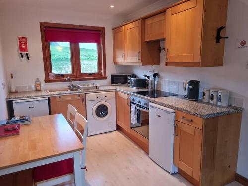 a kitchen with wooden cabinets and a counter top at Kings Reach - Crinan Cottage in Lochgilphead