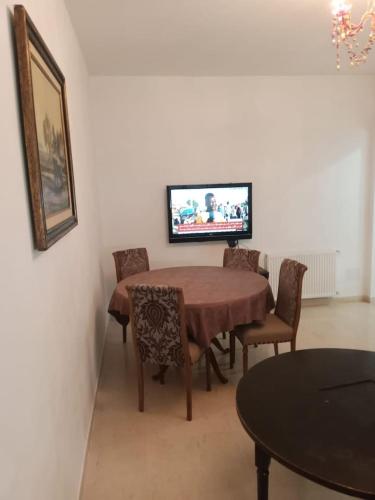 a dining room with a table and chairs and a television at Appartement propre près de l'ENIS in Sfax