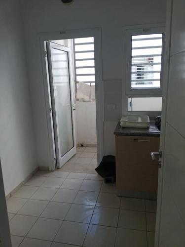 een keuken met een deur naar een kamer met een aanrecht bij Appartement propre près de l'ENIS in Sfax