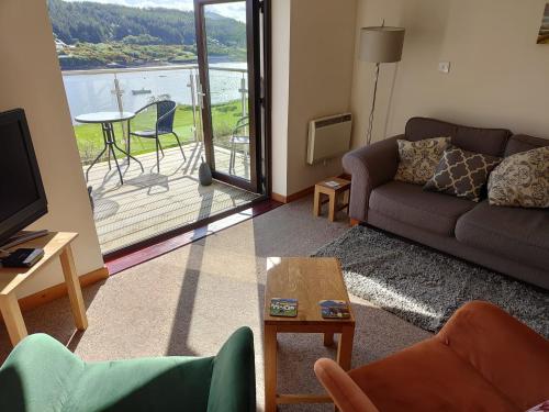 a living room with a couch and a television and a balcony at Castle View Apartment in Dunvegan