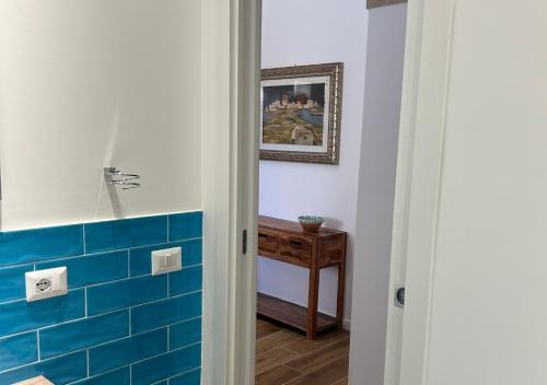 uma casa de banho com azulejos azuis nas paredes e uma mesa em A' BITTA em Favignana