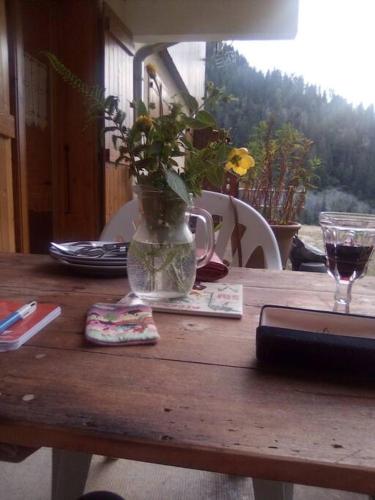 une table en bois avec un vase et des fleurs. dans l'établissement L'appartement LES BOSSONS en lisière de forêt dans le chalet Génépi, à Arêches