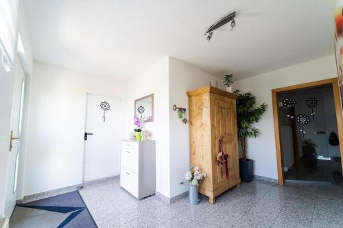 a room with a white wall and a wooden cabinet at Einzigartiger Panoramablick zur Schwäbische Alb in Altenriet