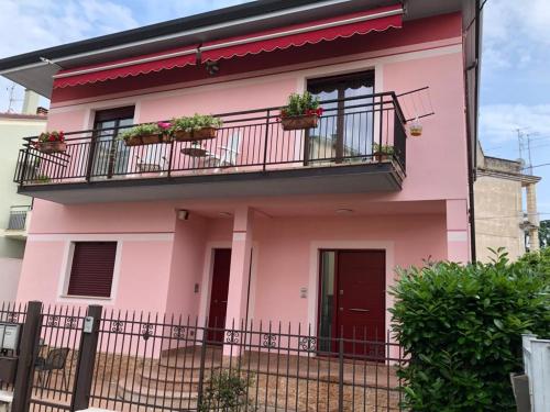 ein rosafarbenes Haus mit einem Balkon und Pflanzen in der Unterkunft CASA PEZZ in Bussolengo