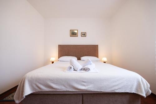 a bedroom with a white bed with towels on it at Villa Ena with Pool & Jacuzzi in Donji Kašić