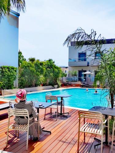 a person sitting on a deck next to a swimming pool at Libyan Princess in Palaiochóra