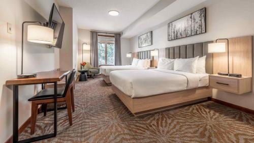 um grande quarto de hotel com duas camas e uma secretária em Blackstone Mountain Lodge by CLIQUE em Canmore