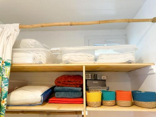 a closet with wooden shelves with towels and baskets at Kapumati Villa - Évasion en Martinique in Sainte-Anne