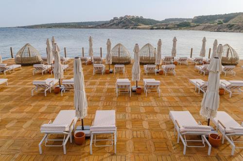 a group of chairs and umbrellas on the beach at Blue Sea Karpasia Hotel in Rizokarpaso