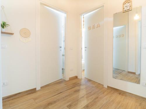 pasillo con paredes blancas, suelo de madera y espejo en B&B La Villa 3.0, en Nonantola