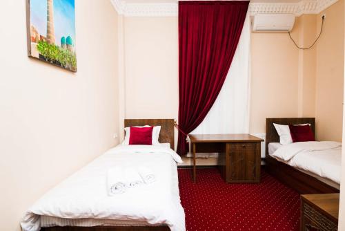 Cette chambre comprend 2 lits et un tapis rouge. dans l'établissement Boutique hotel Shakh, à Boukhara