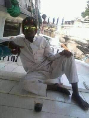 un hombre sentado en un banco con una bebida en Whita rose en Naj‘ al ‘Amrāb