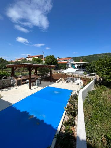 a blue swimming pool in a yard with a house at Bonvivan House in Diminići