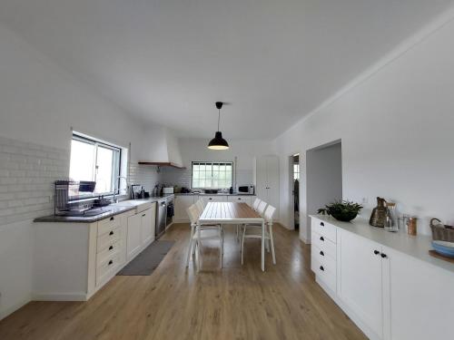 uma cozinha com armários brancos e uma mesa em Monte na Barragem de Montargil com piscina em Montargil