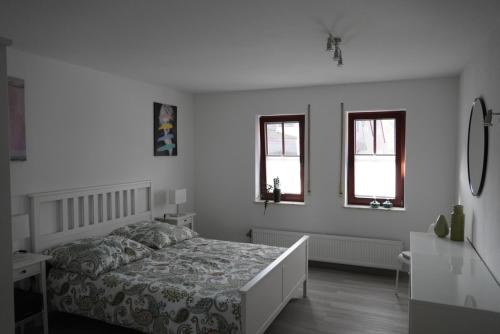a white bedroom with a bed and two windows at schöner als Zuhause - Ferienwohnung in Butzbach in Butzbach