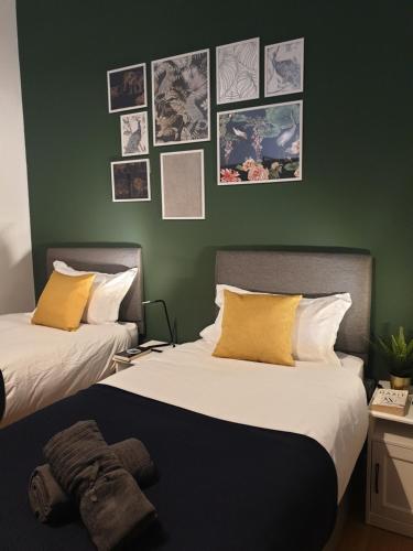 - 2 lits dans une chambre avec des photos sur le mur dans l'établissement Platinum Apartment Birmingham- Free Secure Parking- Fast Fibre Wi-Fi, à Birmingham