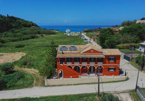 pomarańczowy budynek na wzgórzu nad oceanem w obiekcie Logas Beach Studios Peroulades Corfu w mieście Peroulades