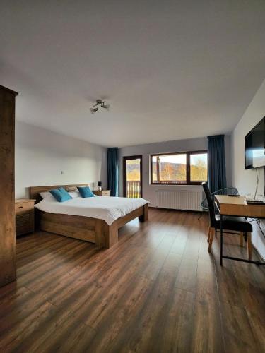 a bedroom with a bed with blue pillows and a desk at Pensiunea Sara pe deal in Hangul