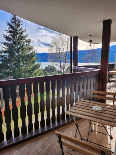 a balcony with a wooden bench and a large window at Pensiunea Sara pe deal in Hangul