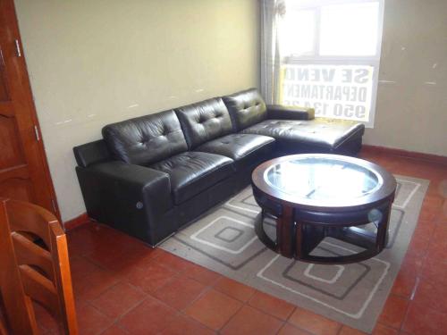 een woonkamer met een zwarte leren bank en een tafel bij Vane House in Lima