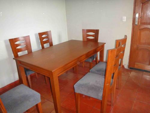 een houten tafel met vier stoelen en een houten deur bij Vane House in Lima