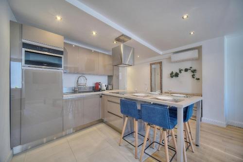 une cuisine avec un îlot doté de tabourets de bar bleus dans l'établissement IMMOGROOM - Heart of the Suquet - City center - Modern, à Cannes