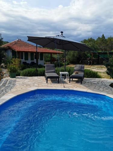 einen Pool mit 2 Stühlen und einem Sonnenschirm in der Unterkunft Apartment Maslina in Vrboska