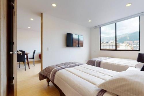 - une chambre blanche avec 2 lits et une fenêtre dans l'établissement Apartamento KANNA-402, à Bogotá