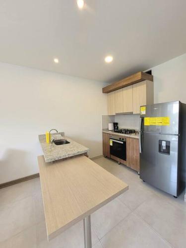 a kitchen with a table and a stainless steel refrigerator at Cali piso 4-06 Pance Apartamento Moderno Exclusivo Sector in Cali