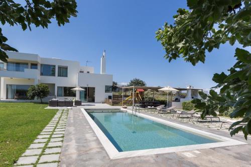 a swimming pool in front of a house at Lux Villa Mia with Heated Pool, 2km to Beach & Childrens Area! in Mikro Metochi