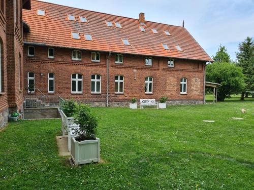 a large red brick building with a bench in the yard at Gutshof Kämmerich - Fewo "Siebenschläferhöhle" in Altkalen