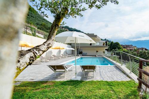 a swimming pool with an umbrella and chairs and a house at GARNI' FOCI in Riva del Garda