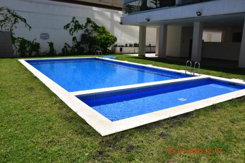 a blue swimming pool in the grass next to a building at Sea view and Ifach Calpe in Calpe