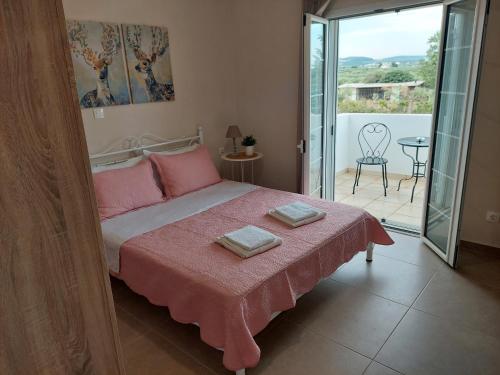 1 dormitorio con 1 cama con sábanas rosas y balcón en Kastro Apartments, en Kalivia Poligirou