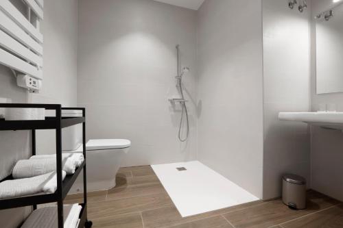 a white bathroom with a shower and a toilet at Mendi Azpi Rooms in Mutriku