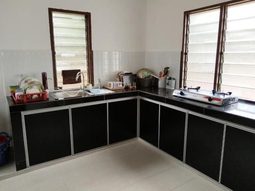 una cocina con armarios negros y fregadero en KJS Homestay, Layang-Layang, Johor, en Kangkar Lanjut