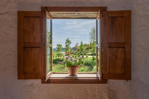 una ventana con una maceta de flores en el alféizar de la ventana en Azenha da Lavoura em Barrega, en Celorico de Basto